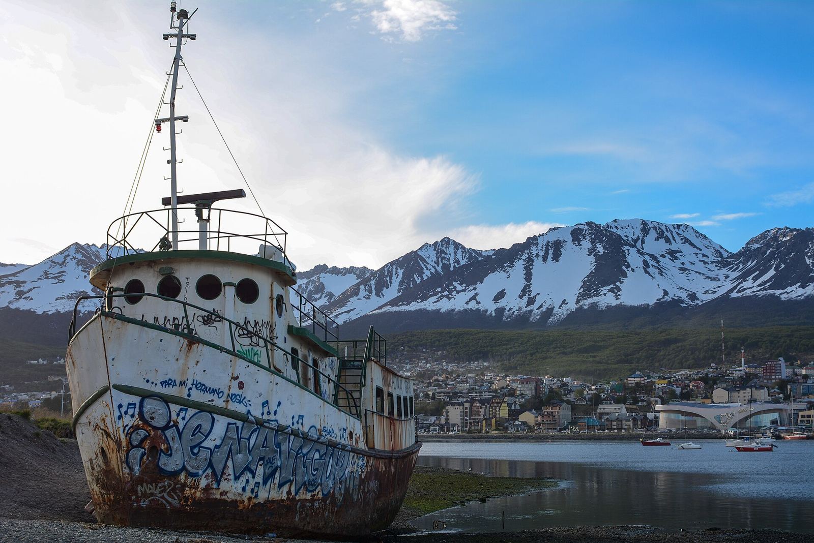 Barco varado en la bahía de Ushuaia, con montañas nevadas